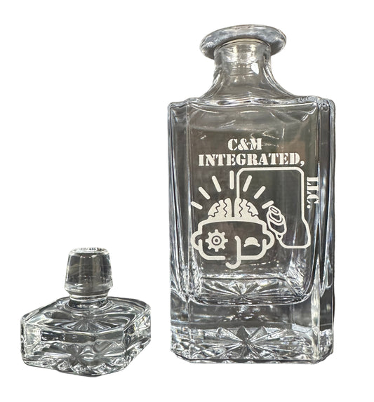 Clear glass decanter with engraved design on a dark surface