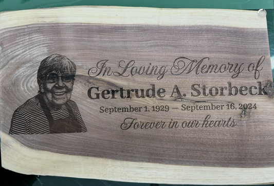 Wooden plaque with engraved text and portrait.